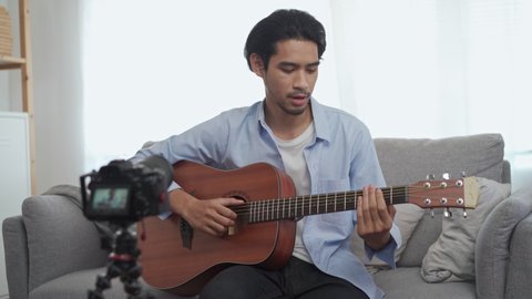 Male vlog influencer performancing music show, teaching how to play guitar, streaming to internet online audience listening at home. Man sing a song with smile face. Home entertainer, blogger concept.
