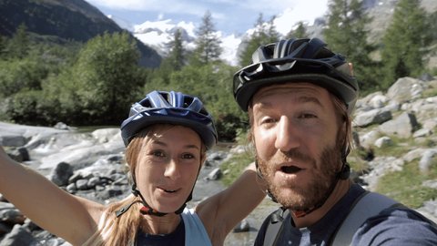 Happy couple taking selfie photo while enjoying mountain biking in summer. People doing sport activities in nature taking selfie 