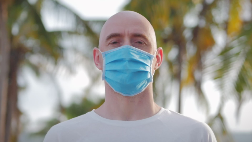 Portrait of a young student man wearing a protective mask on the street, wearing a ovid-19 mask. Health and safety concept, N1H1 coronavirus, virus protection, pandemic. Royalty-Free Stock Footage #1052918918