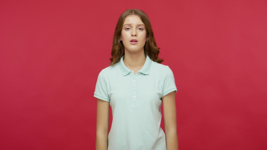 Please, god! Worried, imploring young woman in polo t-shirt sincerely praying and looking up with pleading expression, begging apology, beseeching with hopeful face. indoor studio shot, isolated Royalty-Free Stock Footage #1052921432