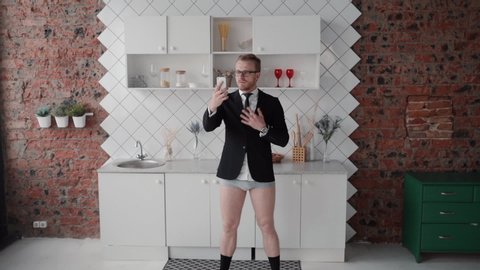 serious businessman having phone video call at home. talking with colleagues wearing suit and underwear underpants. onlie conference conversation, telework. concept quarantine, kitchen