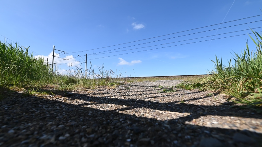 4K 30FPS Low angle timelapse of a dutch railroad in the netherlands. Yellow trains passing by through a natural environment. Starting a new journey through a more sustainable way of traveling.