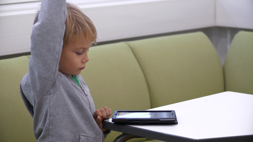 Static shot of a boy, studying on his tablet, in a elementary school classroom, in Finland