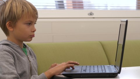 Static shot of a boy, focused, learning the use of a computer in education, in a classroom, at a school, in Finland