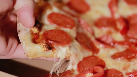 Slice of hot pepperoni pizza. Human hand taking pieces slices of hot tasty italian pizza from open box, food delivery
