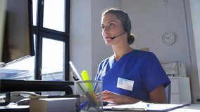 medicine, technology and healthcare concept - female doctor or nurse with headset and computer working at hospital