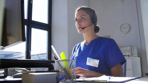 medicine, technology and healthcare concept - female doctor or nurse with headset and computer working at hospital