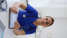 healthcare, medicine and technology concept - female doctor with stethoscope, pen and clipboard talking or having online consultation, vertical view orientation