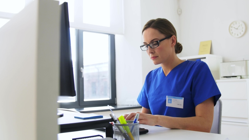 medicine, technology and healthcare concept - tired female doctor or nurse in glasses with computer working at hospital Royalty-Free Stock Footage #1052930030