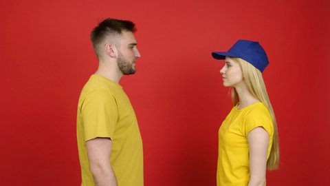 Young woman putting different caps on her boyfriend against color background