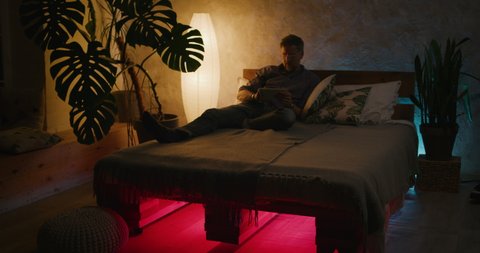 Full shot of a man switching lighting on and off with home hub in a smart home Stockvideó