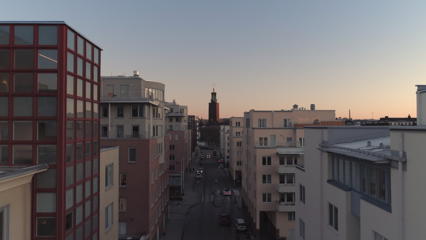 Aerial view of Stockholm street and City Hall building at sunset. Drone shot flying up over street and office buildings, Town Hall tower in the background Royalty-Free Stock Footage #1052935226