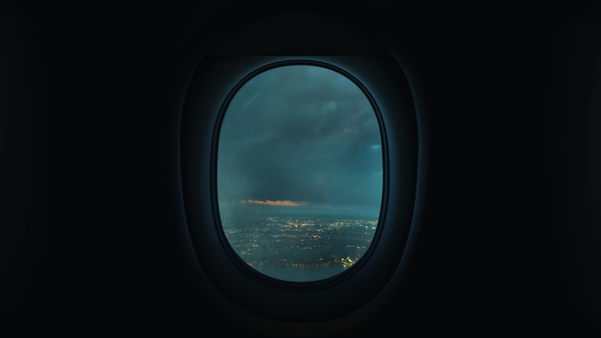 Airplane window view plane flying through storm turbulence with lightning over coastal city Royalty-Free Stock Footage #1052938277