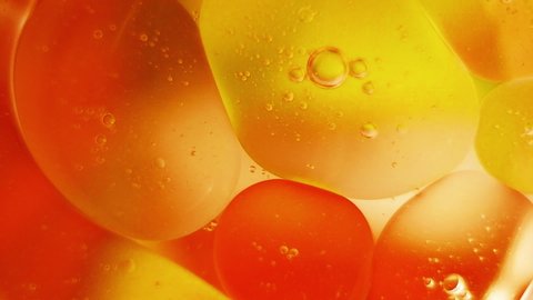 Oil drops, bubbles, on the water surface, motion abstract red and yellow background.