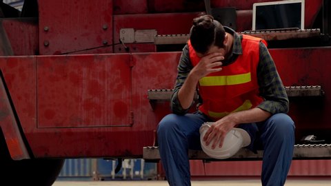 panning video shot of engineers are sitting on a forklift in a transportation industry site. He is very tired at work
