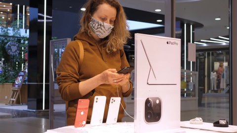 Woman In Protective Mask Choosing New Smartphone At Apple Store. Coronavirus, COVID-19, Sale, Discount, Pandemic Concept. Bialystok, Poland, 20 May, 2020. 
