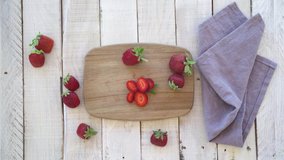 4k video of a woman's hands cutting red strawberries on a wooden board. Concept of healthy life and diet.