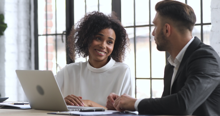 Smiling young african ethnicity businesswoman making agreement with male partner, shaking hands, establishing partnership. Confident businessman signing contract document deal with biracial client. Royalty-Free Stock Footage #1052947382