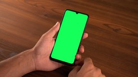 Man browsing phone by swiping on green screen phone, available with alpha/luma matte, as well as transparent layer.