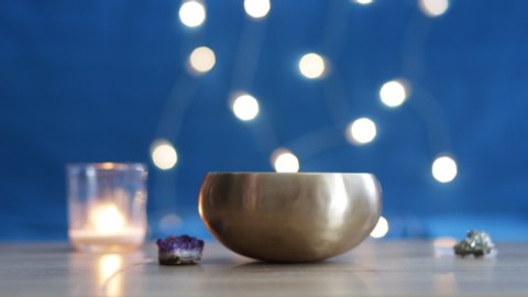 A Tibetan singing bowl is used for spiritual practices. Tibetan singing bowl at the table with candle and crystals. Meditative concept. Meditation at home, alternative medicine. 