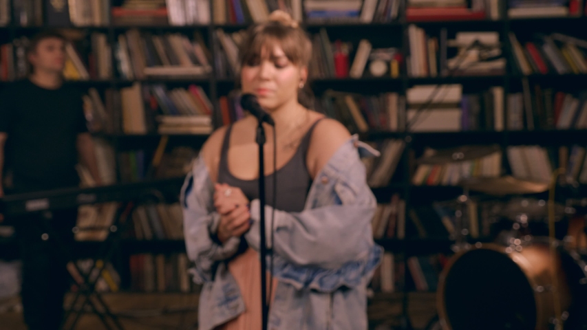 Dolly shot focused pretty female soloist surrounded by professional musicians enjoying live session in studio medium shot music band having rock performance