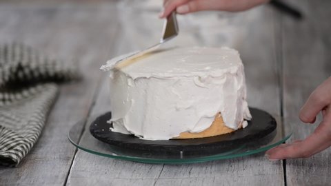 A confectioner prepares a cream cake. Dessert on a white table in the kitchen. The concept of home baking, cooking cakes.