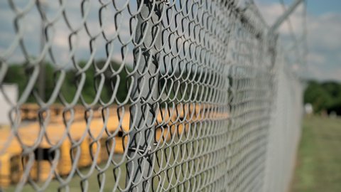 School buses sit behind barb wire fence at county lot due to coronavirus pandemic and remain unused.