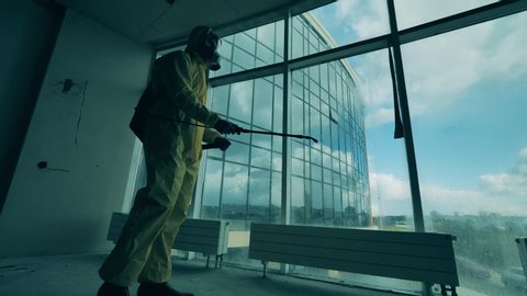 Sanitary worker is disinfecting panoramic windows in an empty room