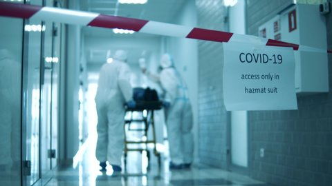 Quarantined corridor with doctors transporting a patient along it. Covid-19 concept.