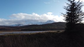 4K Tracking shot of Scottish countryside showing roadside, trees, sky, mountains and lake 
