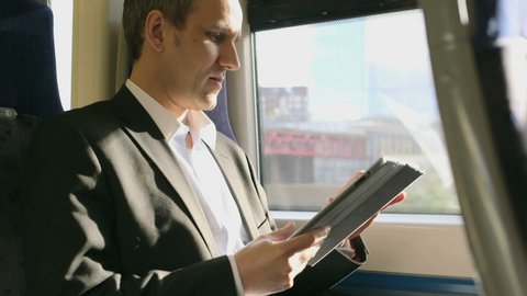 MS Business Man types into his digital tablet on a train