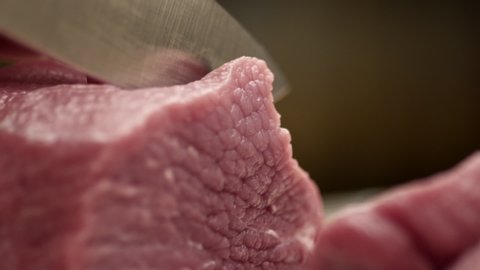 Raw meat cutting with a sharp knife close up