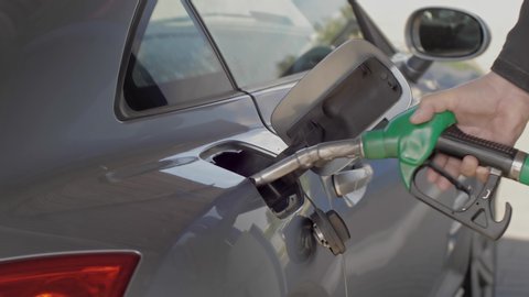 Close up of hand and fuel nozzle into automobile's tank. Fuel, gas station, petrol prices concept. Filling car with gas fuel at station pump.