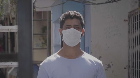 Close up shot of a young confident man wearing protective face mask looking in the camera amid coronavirus or COVID19 epidemic or pandemic