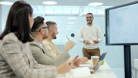 Cheerful Middle Eastern man speaking to group of people in conference room using digital screen with presentation discussing business questions. - Powered by Shutterstock - Get 15% off with code: PIKWIZARD15