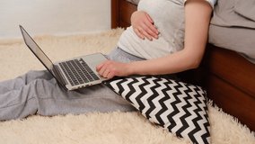 Close up of happy pregnant young woman sitting in living room at home having online consultation with doctor on computer, expectant mother talk on video call consulting with nurse using laptop