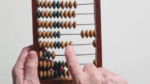 A Elderly Man Is Holding And Moves Wooden Knuckles On A Outdated Vintage Wooden Abacus On A White Background, Close-up. .