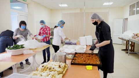 CHERKASY, UKRAINE, MAY 18, 2020: Volunteers are packing Lunchboxes, free meals to be delivered to poor and homeless people during lock down of covid19. Charity project, donating aid, food delivery