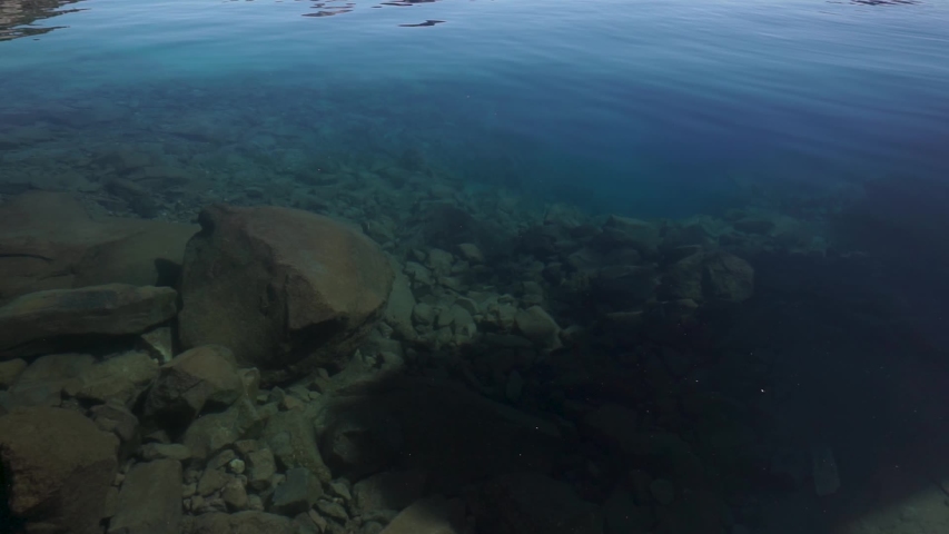 Crater Lake National Park in summer, on beautiful and calm sunny day, surrounded by blue water. Revealing Shot from inside the lake