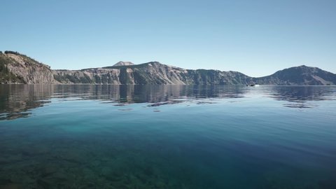 Crater Lake National Park in summer, on beautiful and calm sunny day, surrounded by blue water. Revealing Shot from inside the lake