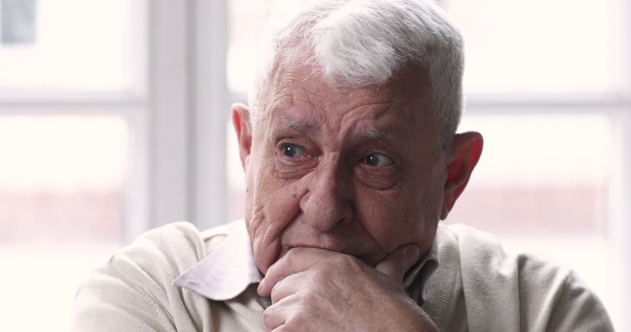 Close up head shot worried unhappy middle aged older man touching chin, grieving alone at home. Nervous lonely senior mature grandfather suffering from health problem, alzheimer parkinson concept. Royalty-Free Stock Footage #1053001445