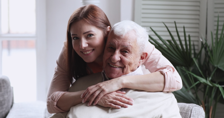 Smiling beautiful grownup daughter cuddling happy middle aged older father, head shot close up. Happy different generations family looking at camera, enjoying sweet tender moment together indoors. | Shutterstock HD Video #1053001448