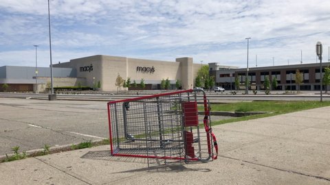 New York, New York / United States - May 15 2020: Macy's department store is closed due to COVID-19 pandemic. Camera pans up from fallen over shopping carte to vacant parking lot.