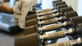 Gym cleaning and disinfection. Infection prevention and control of epidemic. Staff using wipe and alcohol sanitizer spray to clean different weights and dumbbells in gym. - Powered by Shutterstock - Get 15% off with code: PIKWIZARD15