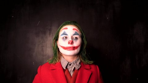 Person in Joker cosplay costume smoking in black office, halloween concept