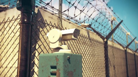 Closeup of CCTV camera in a heavily guarded place with barbed wire fence, prison