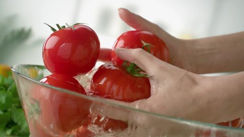A woman is washing tomatoes in slow motion.