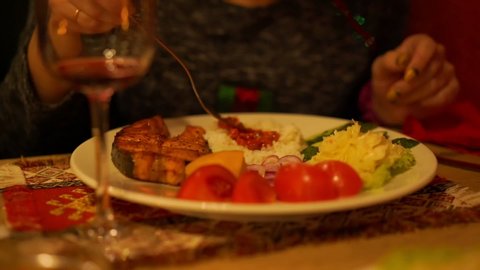 woman with manicure eats rice with delicious red sauce from plate with salmon steak and vegetables closeup slow motion