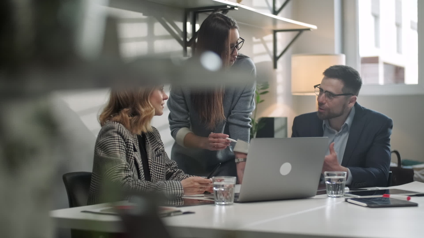In Creative Office Productive Coworkers Standing at the Table, Company Meeting. Colleagues and clients talking strategy with laptop and tablet. Royalty-Free Stock Footage #1053014975