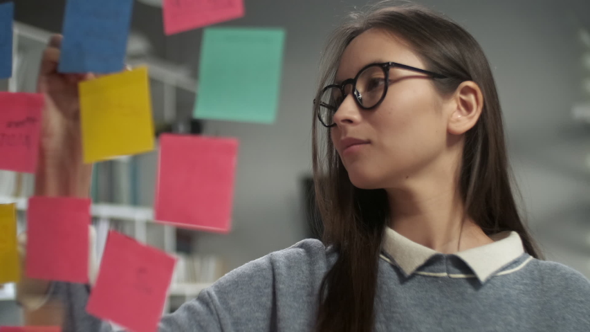 Asian Business Woman Write Tasks Creative Ideas On Sticky Notes On Glass Board, Female Corporate Leader Planning Project On Post It Sticky Notes Organize Work On Stickers | Shutterstock HD Video #1053014990